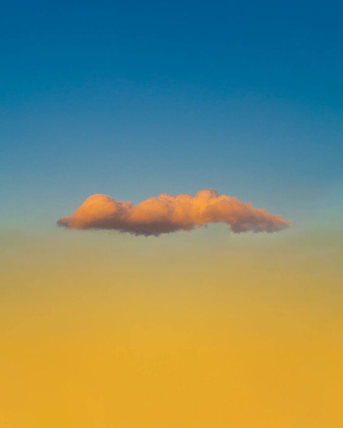 Single orange cloud floating in a blue and yellow sky, showcasing creative photo edits that challenge perception of reality.