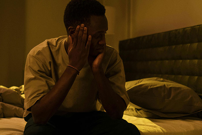 Man sitting on bed looking worried and anxious, illustrating a scary gut feeling of needing to leave immediately.