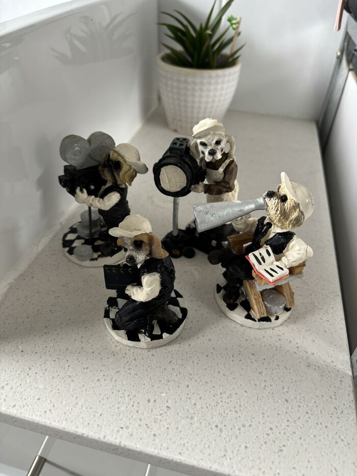 Four thrifted dog figurines as a film crew with camera, megaphone, and script, showcasing weird and wonderful collectible finds.