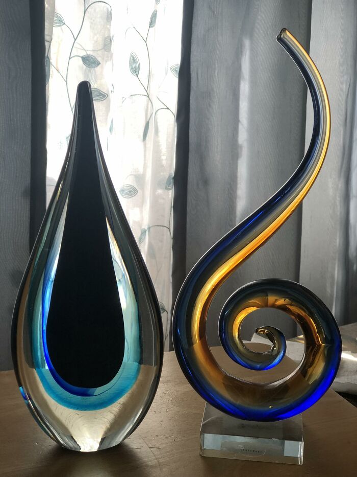 Colorful blown glass thrifted finds with unique shapes displayed on a wooden surface in natural light.