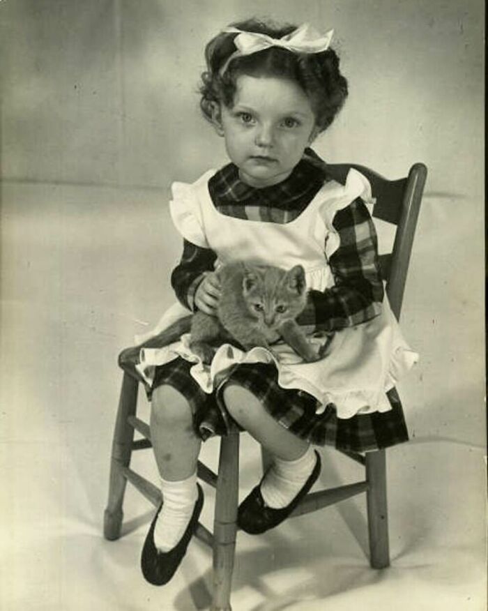 Vintage black and white photo of a little girl holding a kitten, showcasing the timeless bond between kids and cats.