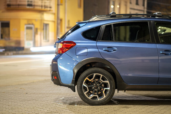Blue crossover car parked on a nighttime city street with blurred lights in the background, reflecting a middle class lifestyle.