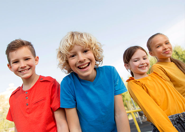 Four smiling kids outdoors, enjoying a candid moment reflecting things everyone does but doesn't talk about.