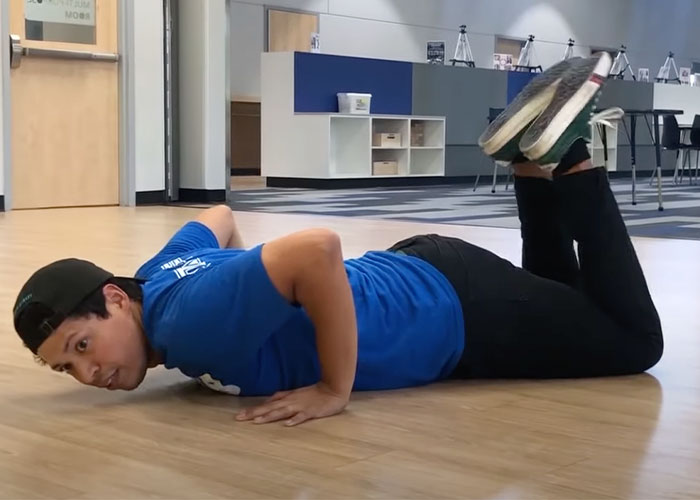 Person in blue shirt and black cap lying on the floor with legs bent, illustrating a scene related to pathetic injuries shared by people.