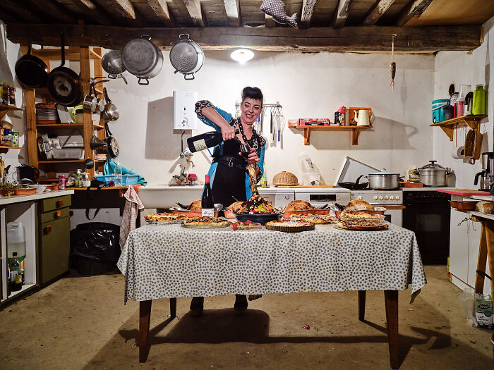 Woman pouring wine at a table filled with delicious dishes in a rustic kitchen, an award-winning food photography shot