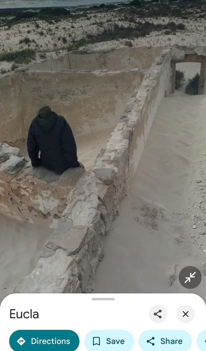 Person sitting inside sandy ruins in a remote area, an odd and intriguing find on Google Earth shared online.