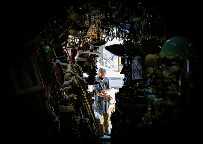 Elderly person organizing cluttered antique shop, illustrating weird habit that means I was raised poor concept.