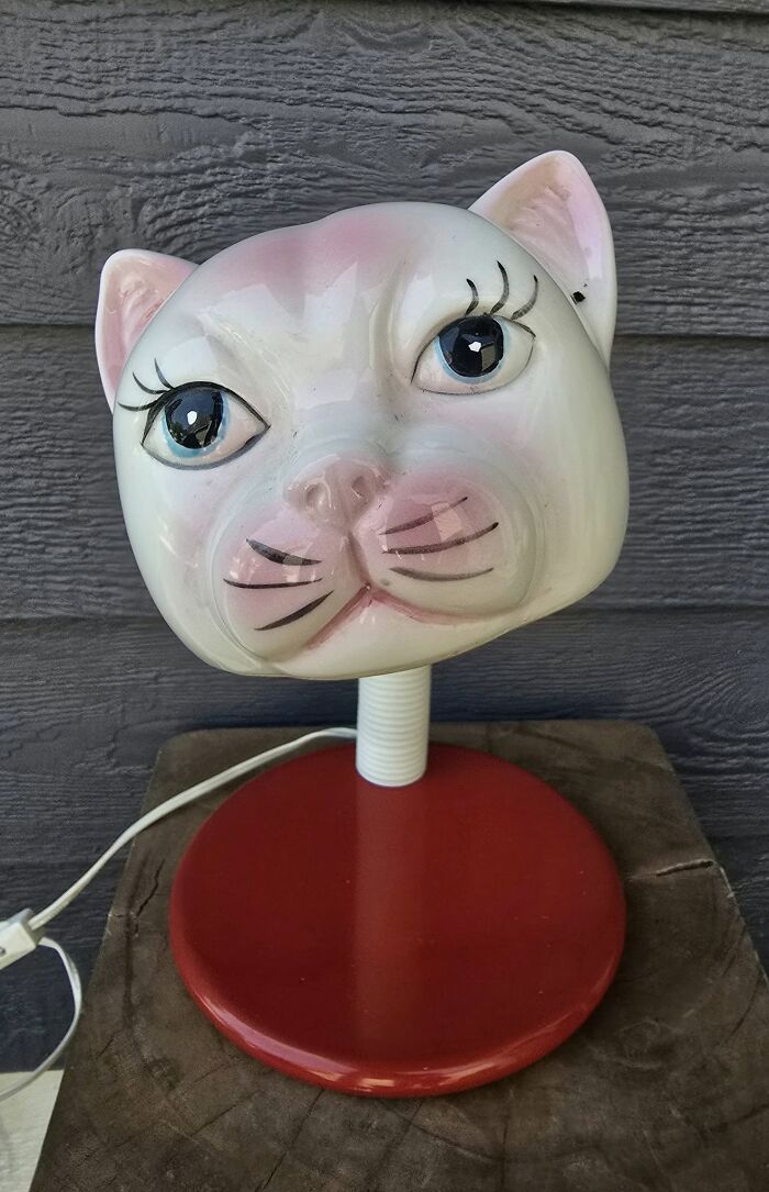Ceramic cat lamp with large eyes and pink accents on red base, a thrifted find that's weird and wonderful.