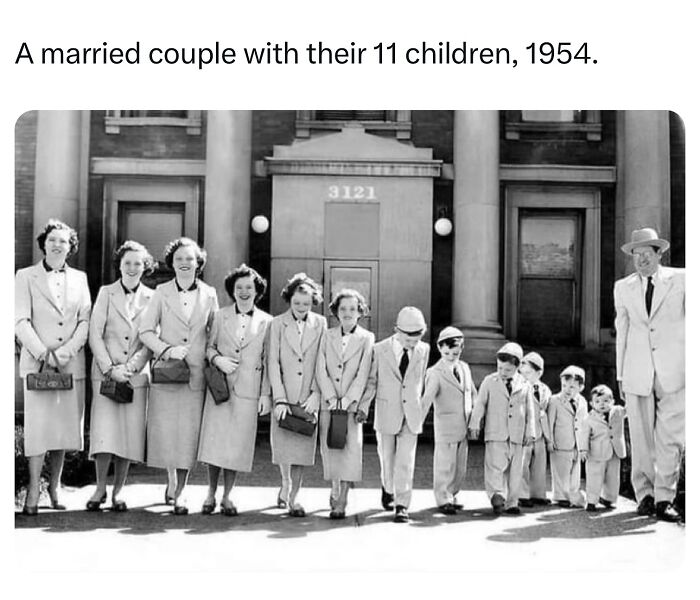 Black and white photo of a married couple with their 11 children in 1954, a monumental life moment frozen in time.