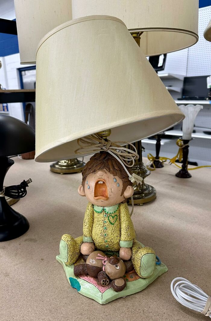 Thrifted lamp with a crying child figurine base holding a teddy bear, showcasing a weird and wonderful vintage find.