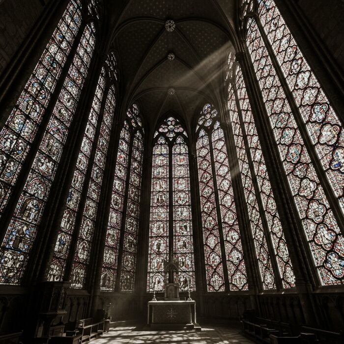 Interior of a historic church with tall stained glass windows and light rays, showcasing a side of history rarely seen.