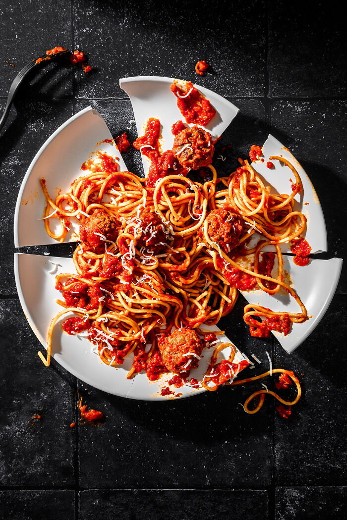 Broken white plate with spaghetti and meatballs in red sauce, featured in world food photography awards.