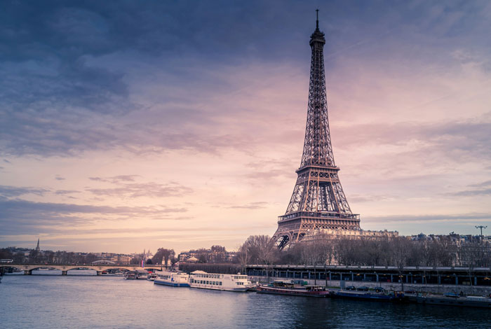 Eiffel Tower at sunset with boats on the river, illustrating stories of strangers unsuccessfully attempted to mug people.