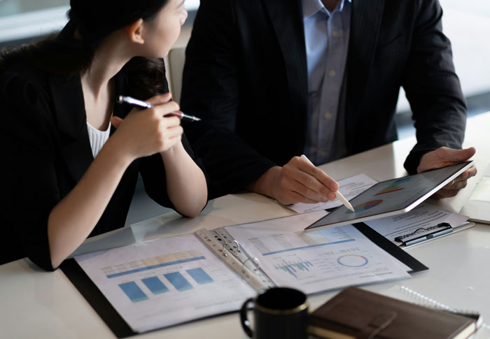 Two professionals reviewing documents and charts during a meeting, illustrating bosses going off the rails.