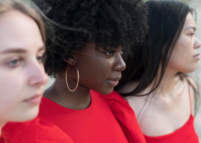 Three women in red tops looking thoughtfully in different directions, illustrating things everyone does but doesn’t talk about.
