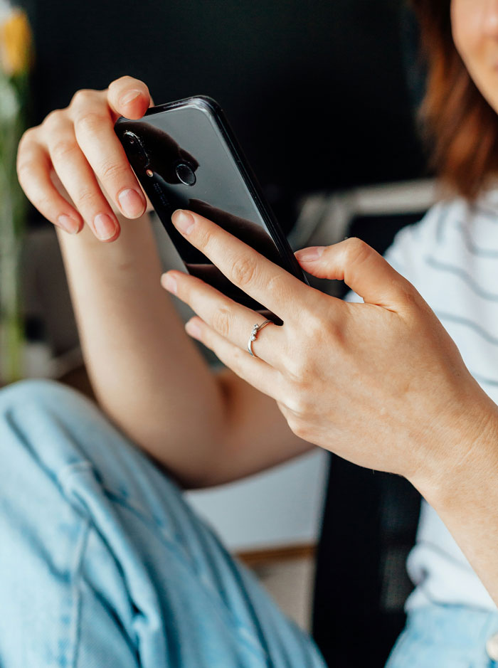 Woman holding smartphone, reflecting on friendship of 10 plus years ended, showing thoughtful emotion and casual setting.