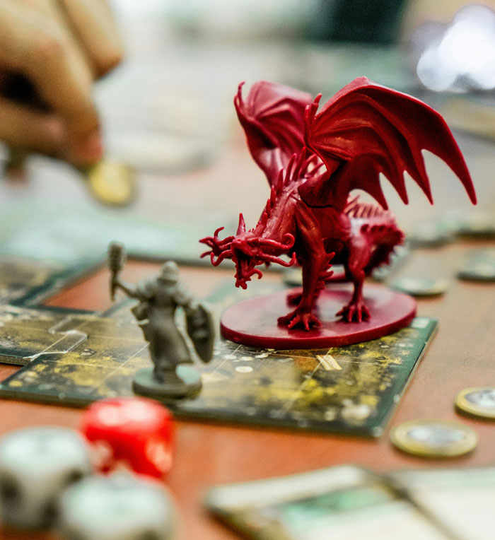 Close-up of tabletop game with detailed miniature dragon and warrior figurines highlighting weird rule gameplay concept.