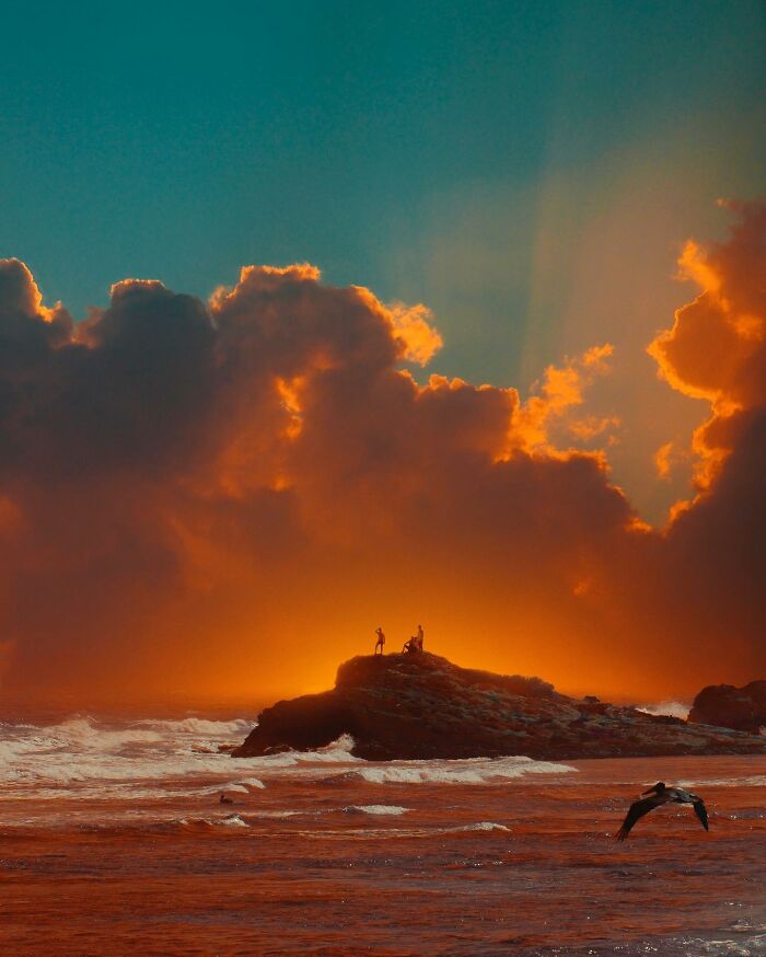 Surreal photo edit of people on rocky shore with vibrant sunset and dramatic clouds, showcasing creative visual lies.