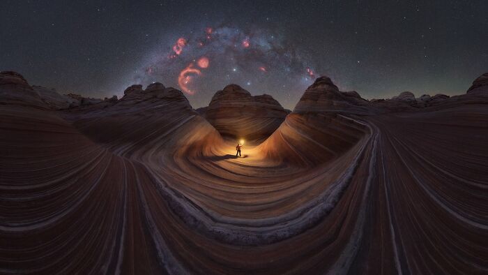 Person holding light in rocky desert under stunning Milky Way shot showcasing the beauty of the night sky.
