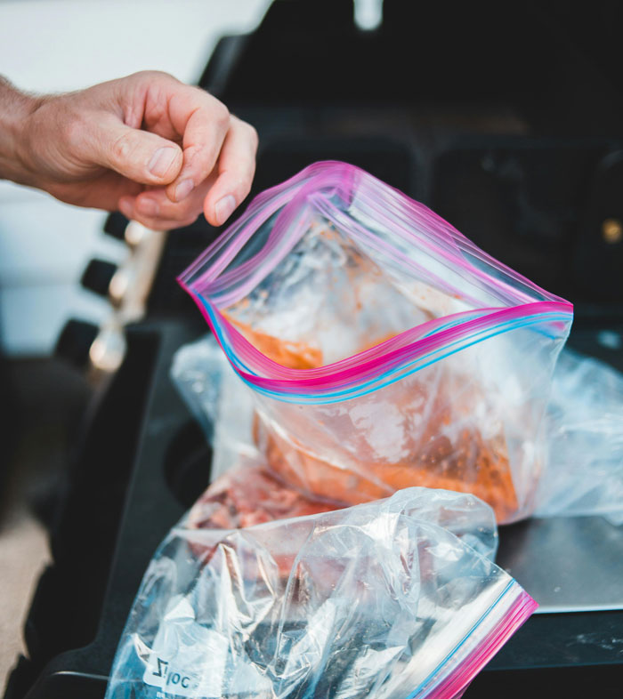 Hand holding a plastic zipper bag with leftover food, illustrating a weird habit related to being raised poor.