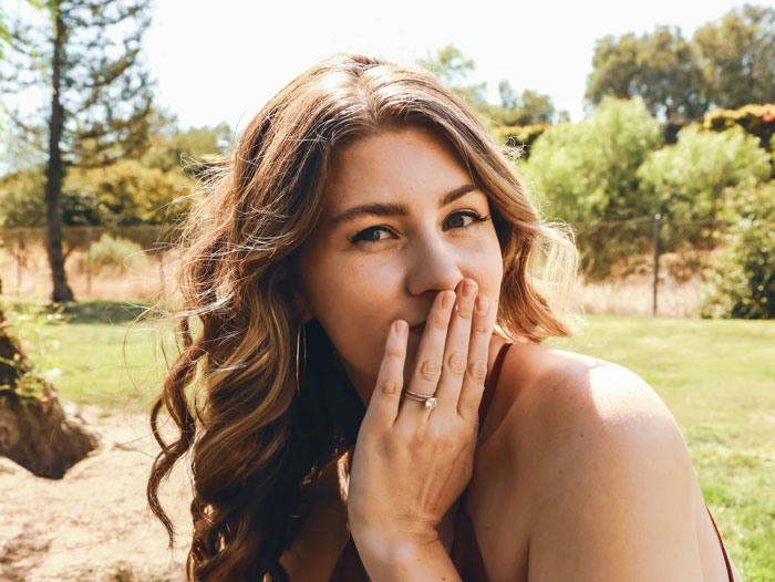 Young woman with long hair covering her mouth outdoors, illustrating problematic behaviors women get a pass for according to men.