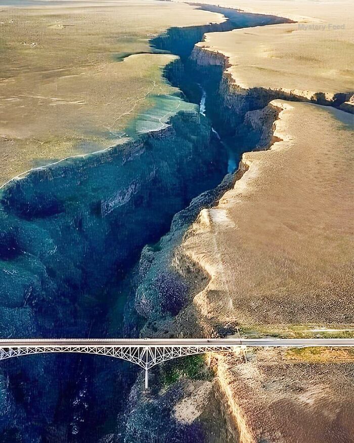 Aerial view of a deep canyon with a white bridge spanning the gap, highlighting fascinating ancient history landscapes.