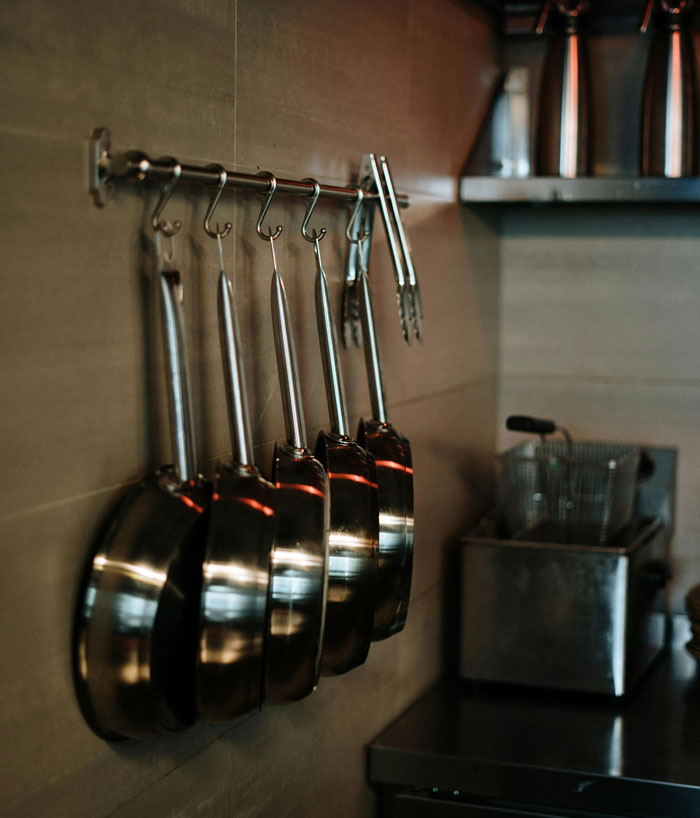 Set of stainless steel pans hanging on hooks in a kitchen, illustrating a weird habit linked to being raised poor.