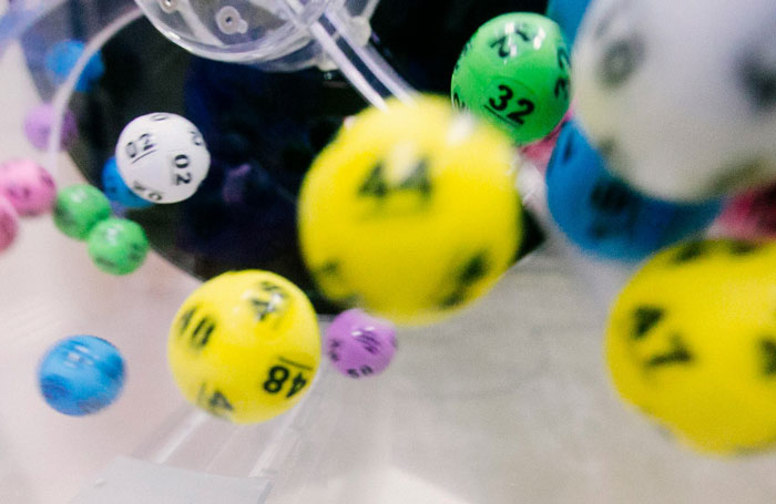 Colored lottery balls with numbers in a machine, illustrating common ways people lose money while thinking they’re saving.