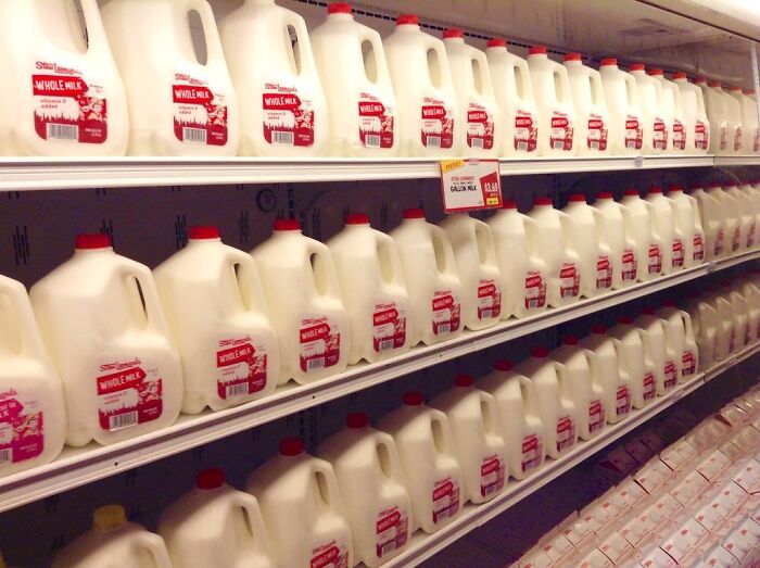 Rows of whole milk gallons on store shelves illustrating food prices comparison from the 1980s and now.