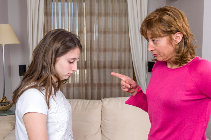 Woman pointing and scolding a younger woman in a living room, depicting soul-crushing things parents told their children.