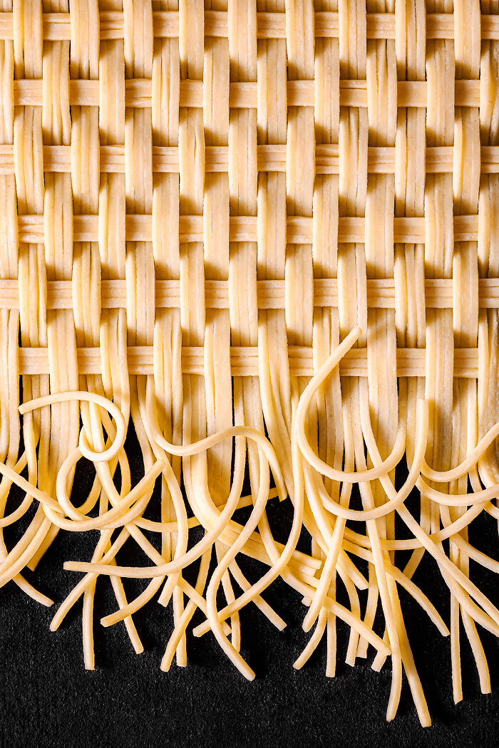 Woven strands of uncooked spaghetti noodles arranged in a creative pattern for food photography awards.