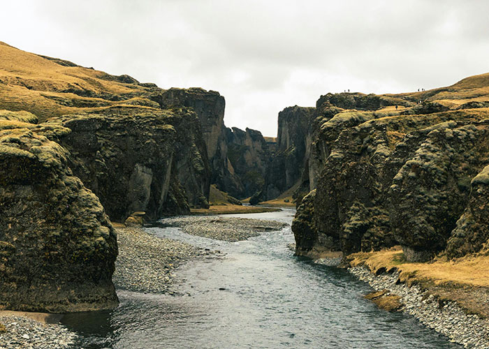 Scenic river flowing through rocky cliffs covered with moss and grass, illustrating entertaining facts about nature landscapes.