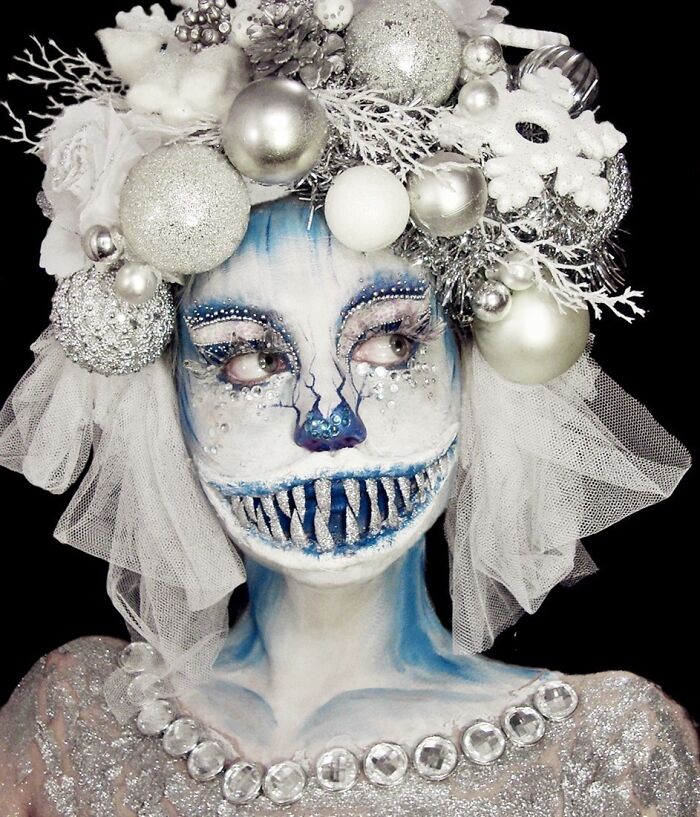 Artistic makeup look with blue and silver face paint and elaborate silver holiday-themed headpiece by talented makeup artist.