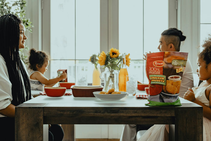 Family seated at dining table enjoying a meal together reflecting on weird parenting rules they thought were normal.