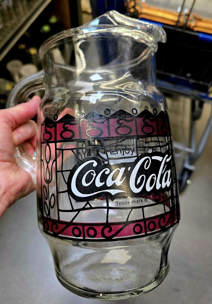 Clear vintage Coca-Cola glass pitcher held by hand, a weird and wonderful thrifted find with unique design.