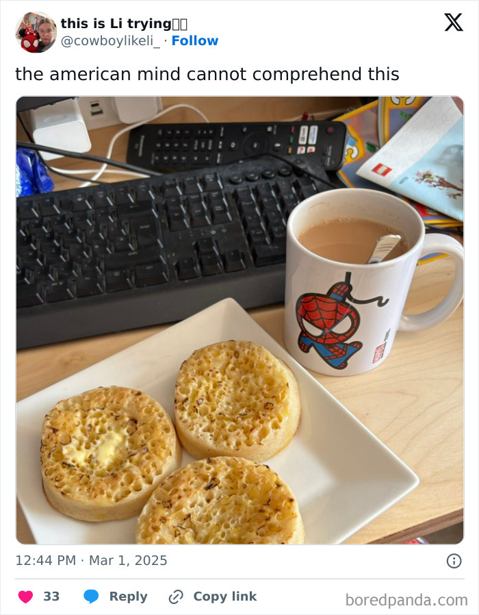 Three crumpets on a white plate with a mug of tea beside a keyboard, illustrating the American mind confusion.