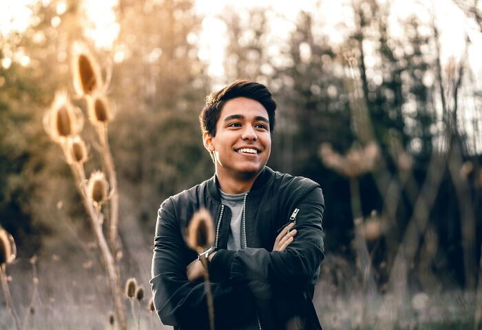 Young man smiling outdoors among tall plants, illustrating cultural differences changing how people see the world.