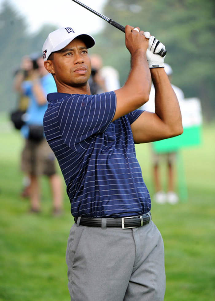 Professional golfer wearing a cap and striped shirt swinging a golf club during a memorable celebrity encounter outdoors.