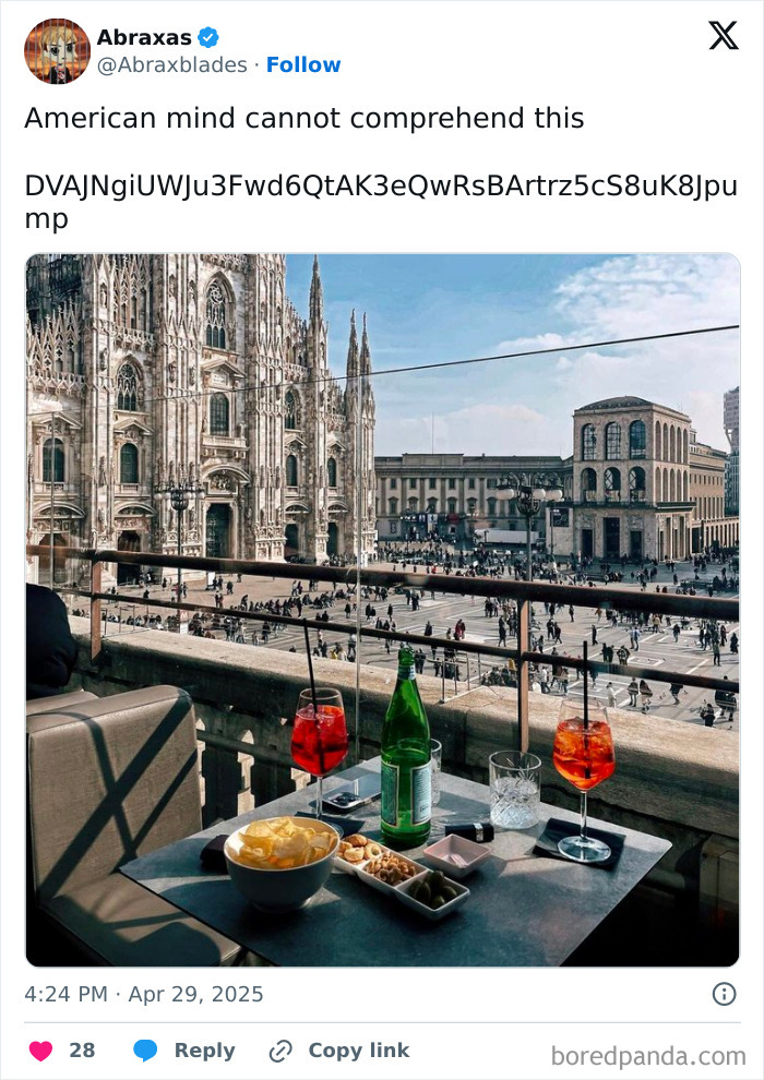 Outdoor table with drinks and snacks overlooking a large crowd near a historic cathedral, highlighting American mind confusion.