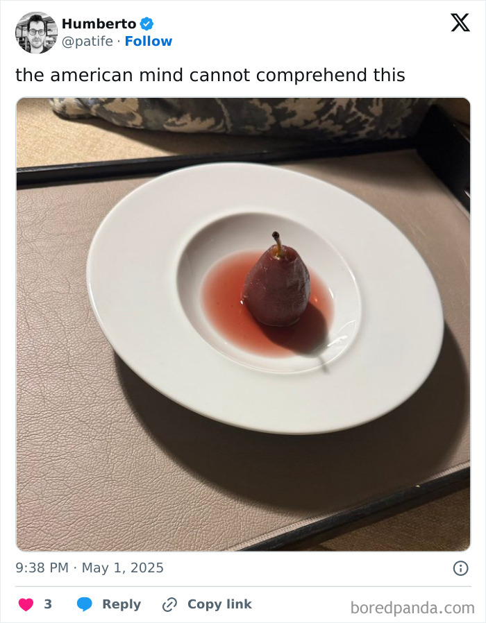 Poached pear in red sauce on a white plate, a confusing image that challenges the American mind comprehension.