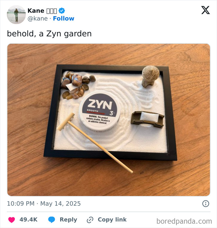 Mini Zen garden with white sand, rocks, a small rake, and a Zyn nicotine pouch container on a wooden table.