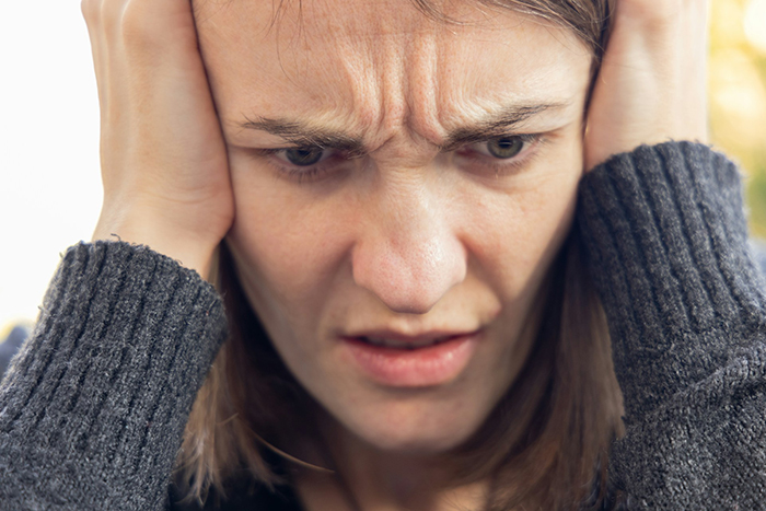 Woman looking worried and upset, suspecting boyfriend is messing with her toothbrush before dumping him.