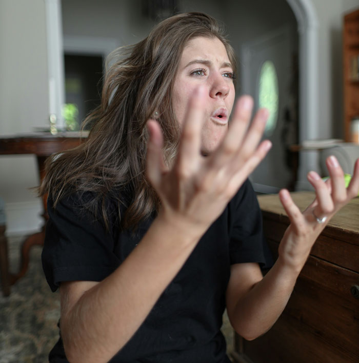 Young woman showing frustrated and emotional behavior indoors, illustrating problematic behaviors women get a pass for according to men.