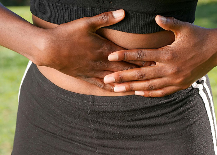 Person wearing black workout clothes holding their stomach outdoors illustrating entertaining facts about health and fitness.