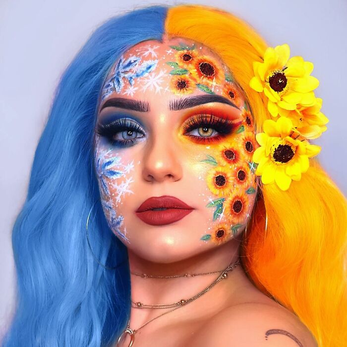 Creative makeup look featuring half blue and half yellow hair with seasonal floral and snowflake face art by talented artists.