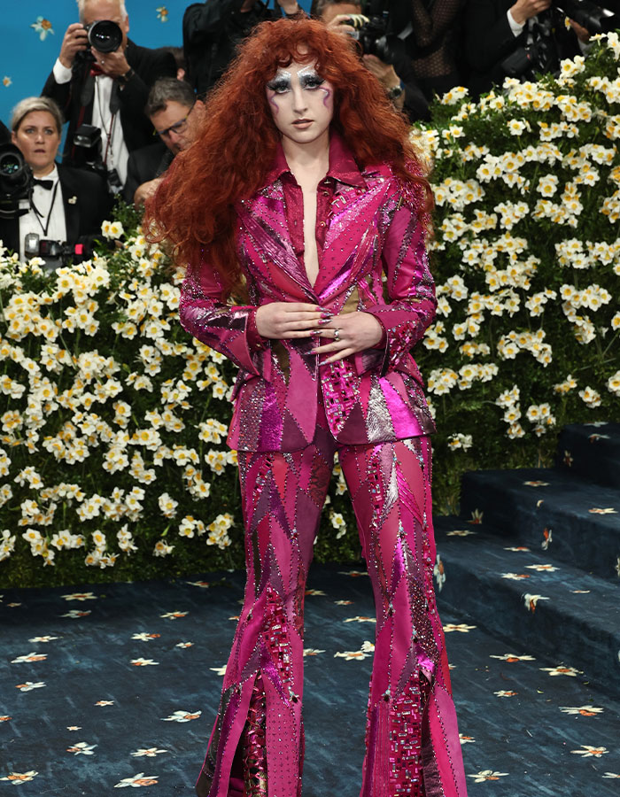Person with bold red curly hair wearing a shimmering pink suit at an event highlighting biggest fashion fails Met Gala 2025