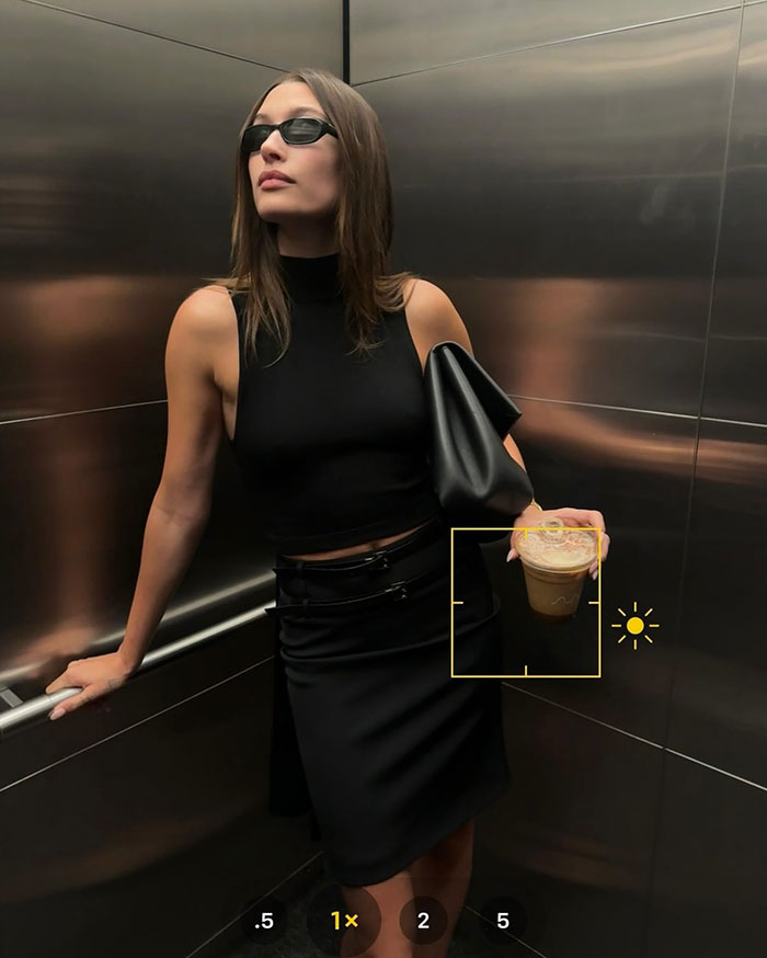 Hailey Bieber wearing black outfit and sunglasses posing in elevator holding a drink after husband Justin’s hockey game tantrum Hailey Bieber wearing black outfit and sunglasses posing in elevator holding a drink after husband Justin’s hockey game tantrum