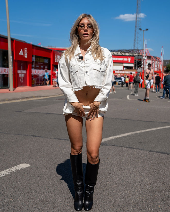 Woman in a cropped white jacket and black boots standing on street, related to Bonnie Blue arrest video and adult star update.