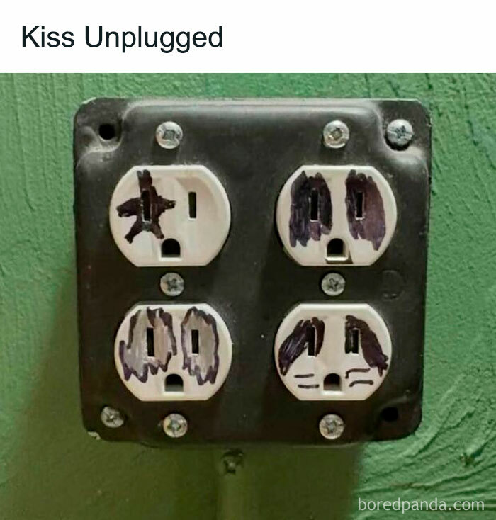 Electrical outlet with faces drawn on plugs, humorously celebrating 80s nostalgia and iconic band imagery.