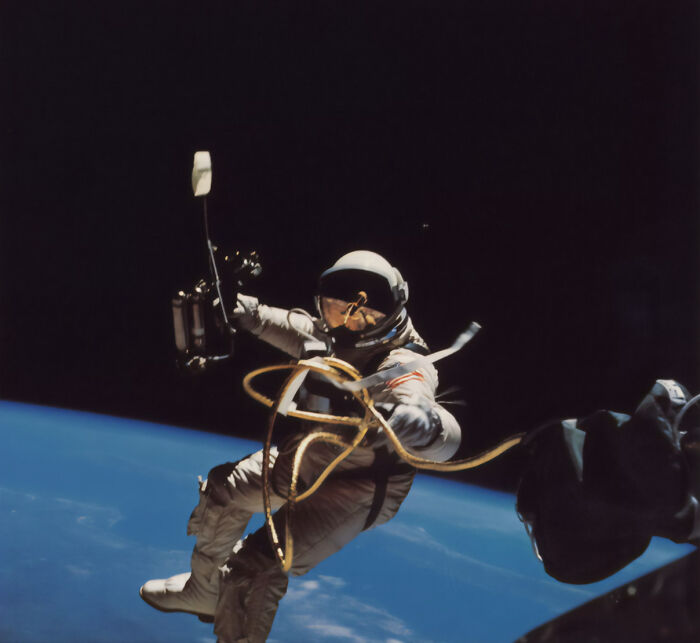 Astronaut in space suit tethered to spacecraft floating above Earth, highlighting struggles after long space missions.